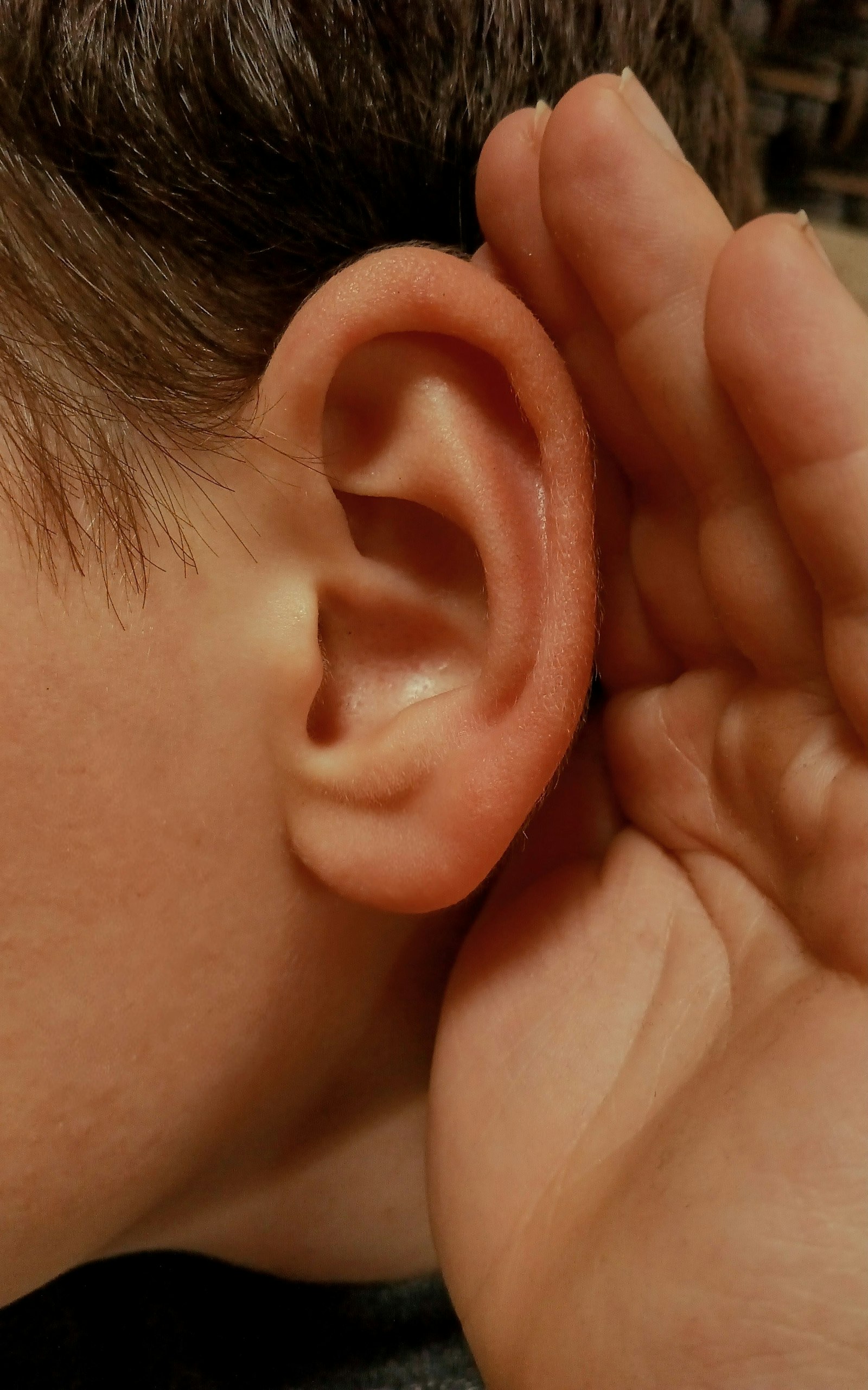 Personne qui tend l'oreille pour écouter attentivement, en écho au thème des acouphènes