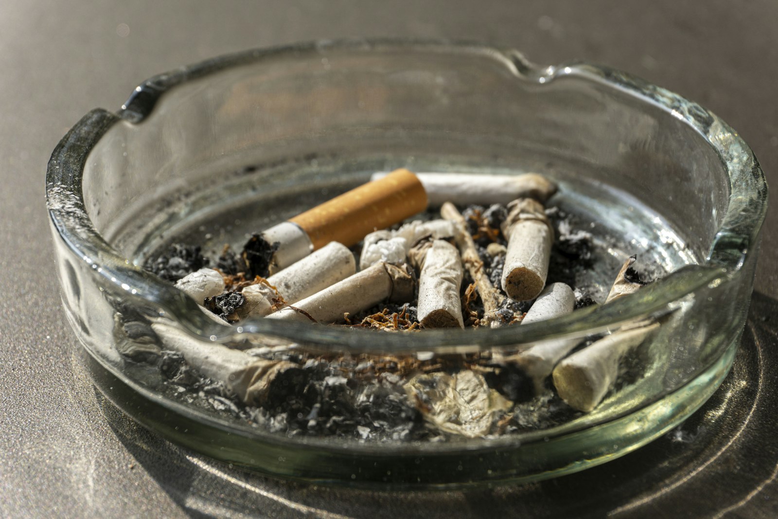 Mégots de cigarettes éteints dans un cendrier en verre