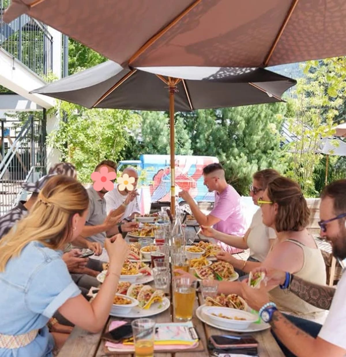 Un groupe d'une dizaine de personnes réunies en terrasse autour d'un repas convivial