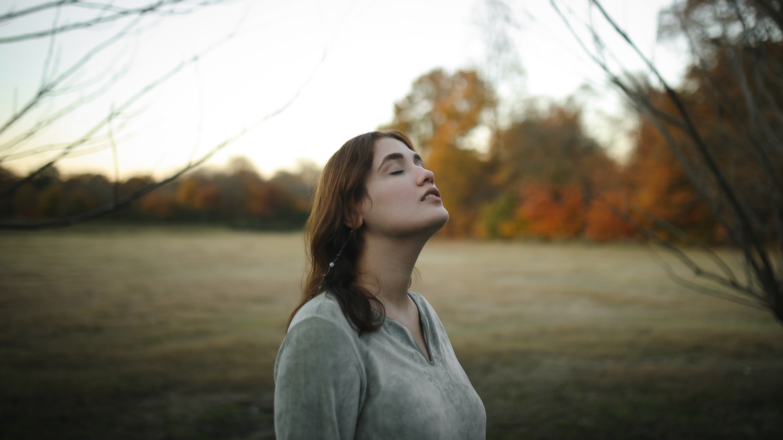 Femme les yeux fermés, respirant calmement en extérieur