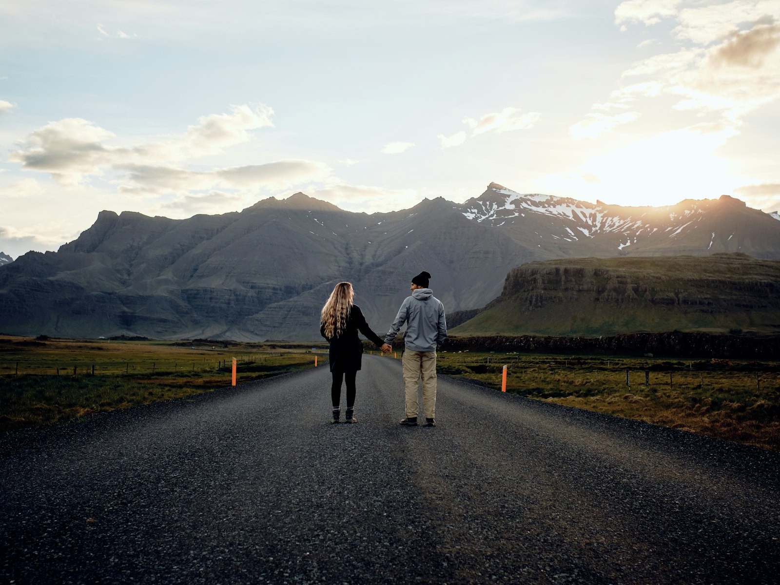 Un couple se tenant la main, marchant ensemble face aux montagnes